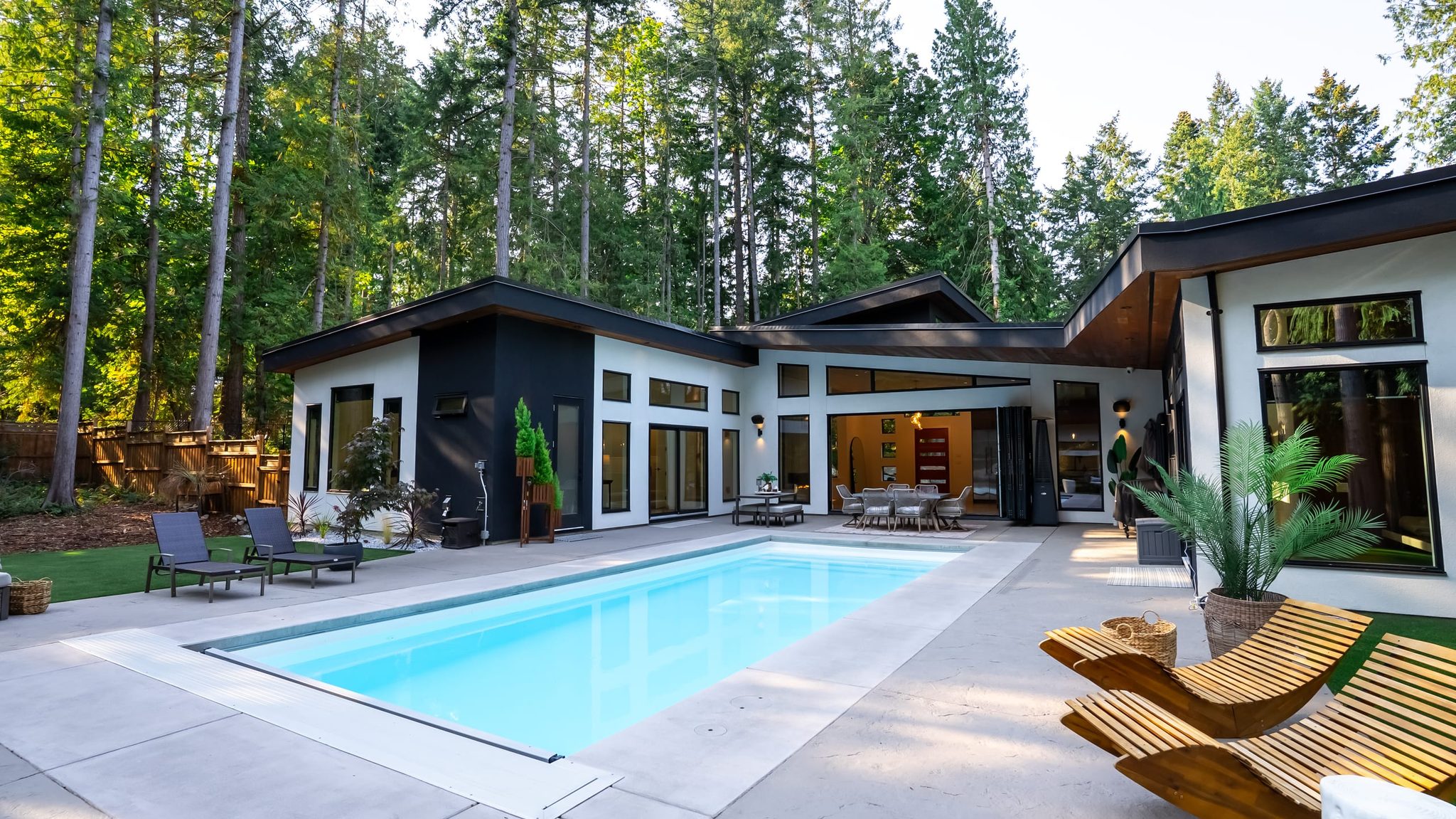 Courtyard pool and single-level modern home framed by tall firs in North Saanich