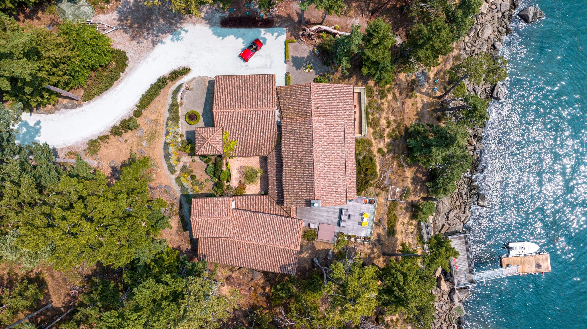 Aerial view of a Tuscan-style oceanfront estate on a rocky point above turquoise water