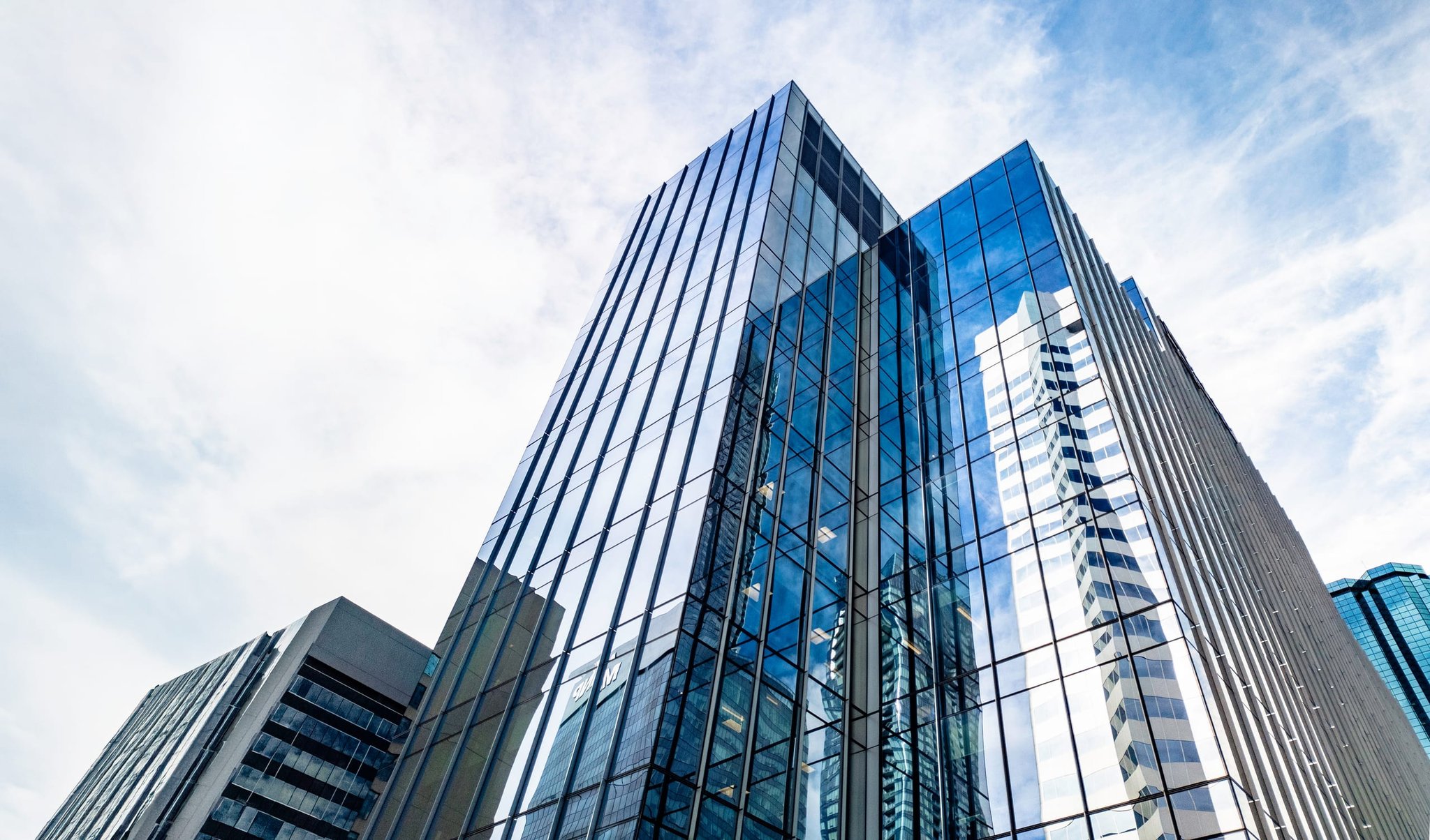 Low-angle view of glass office towers against a bright sky in downtown Edmonton