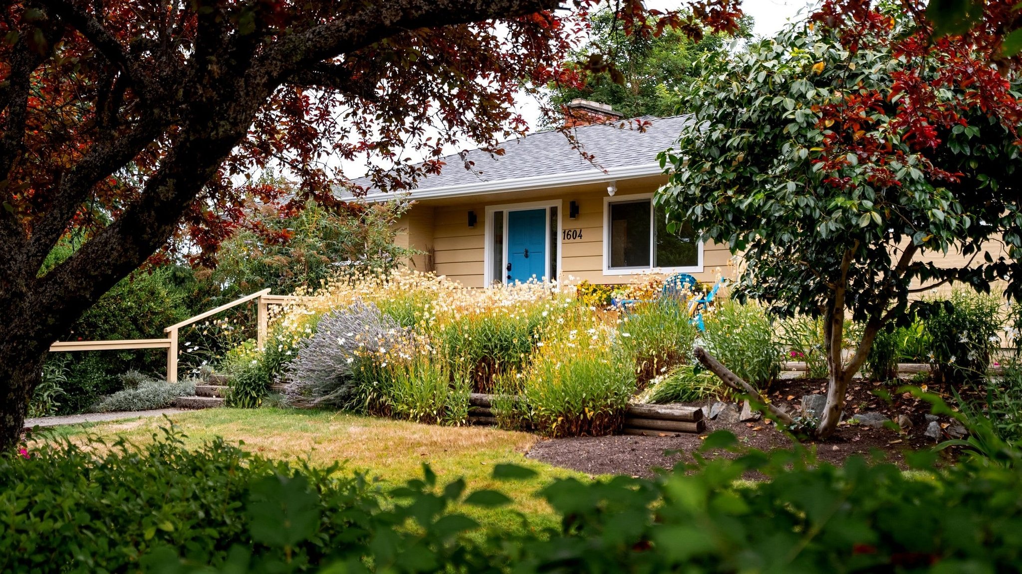 Yellow bungalow exterior framed by garden and fall foliage