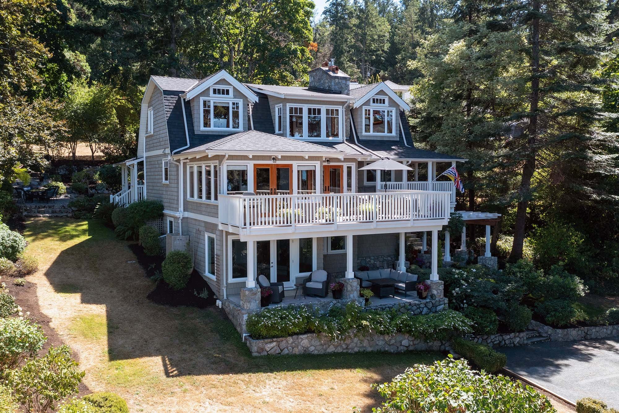 Aerial view of a shingle-style waterfront estate with wraparound porch