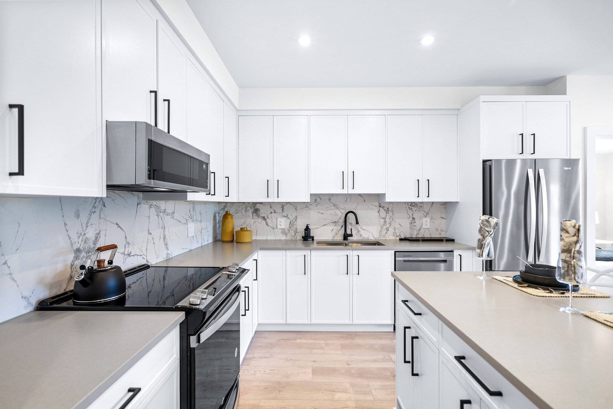 White kitchen with marble backsplash and stainless steel appliances