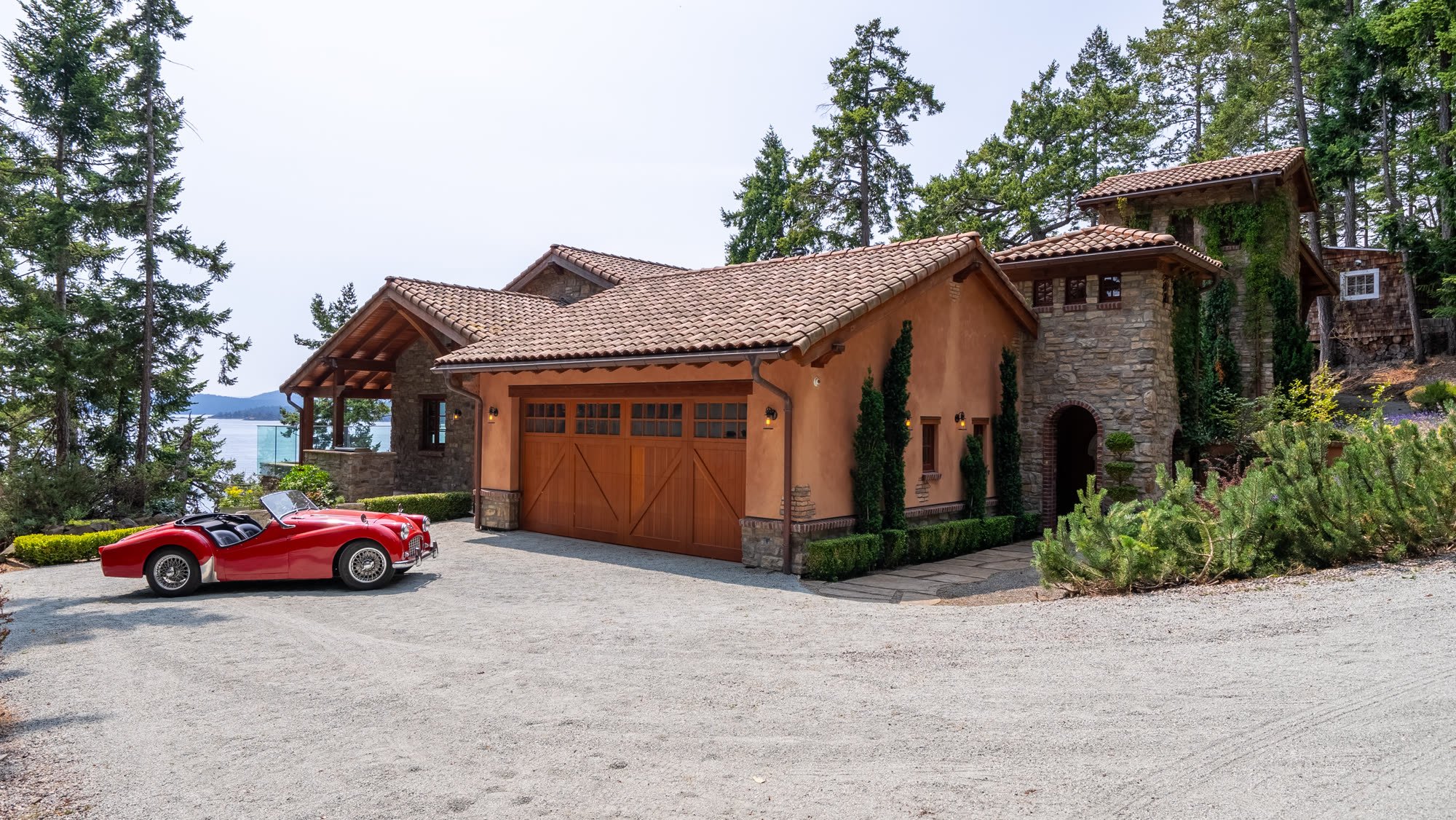 Mediterranean-style estate with an arched stone entry and timber garage doors