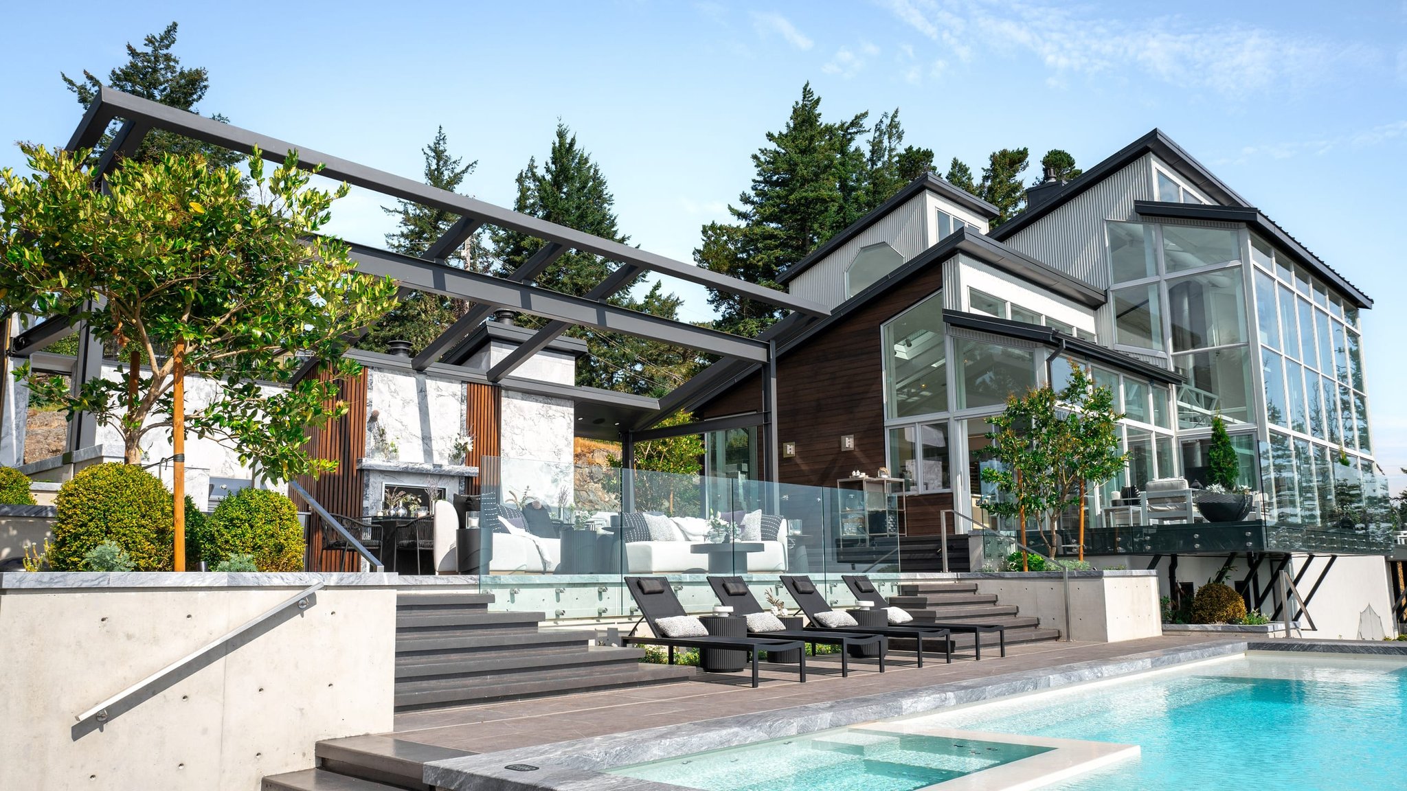Modern custom home with steel beams and glass framing a poolside terrace
