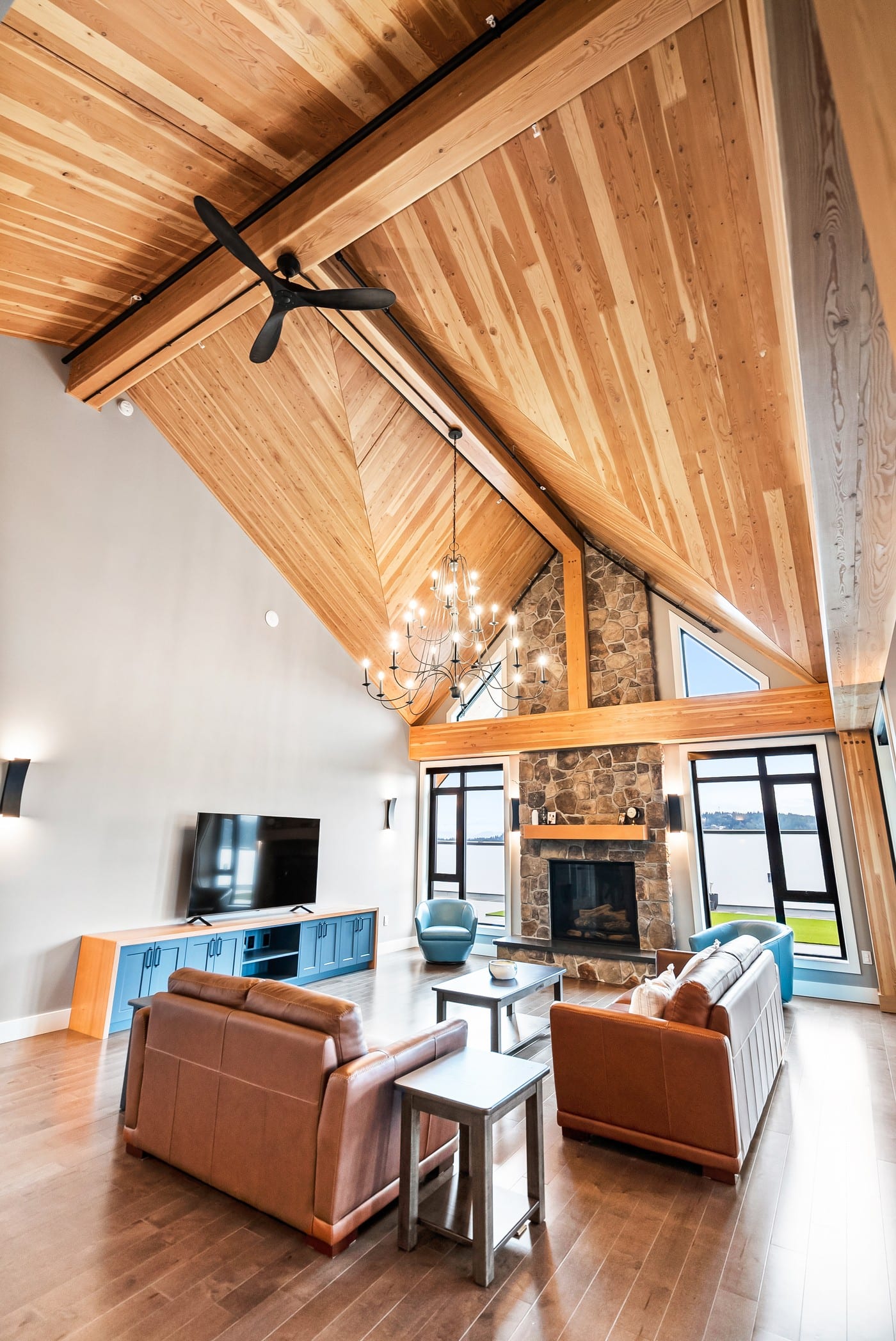 Vaulted great room with a stone fireplace, wood-plank ceiling and lake view