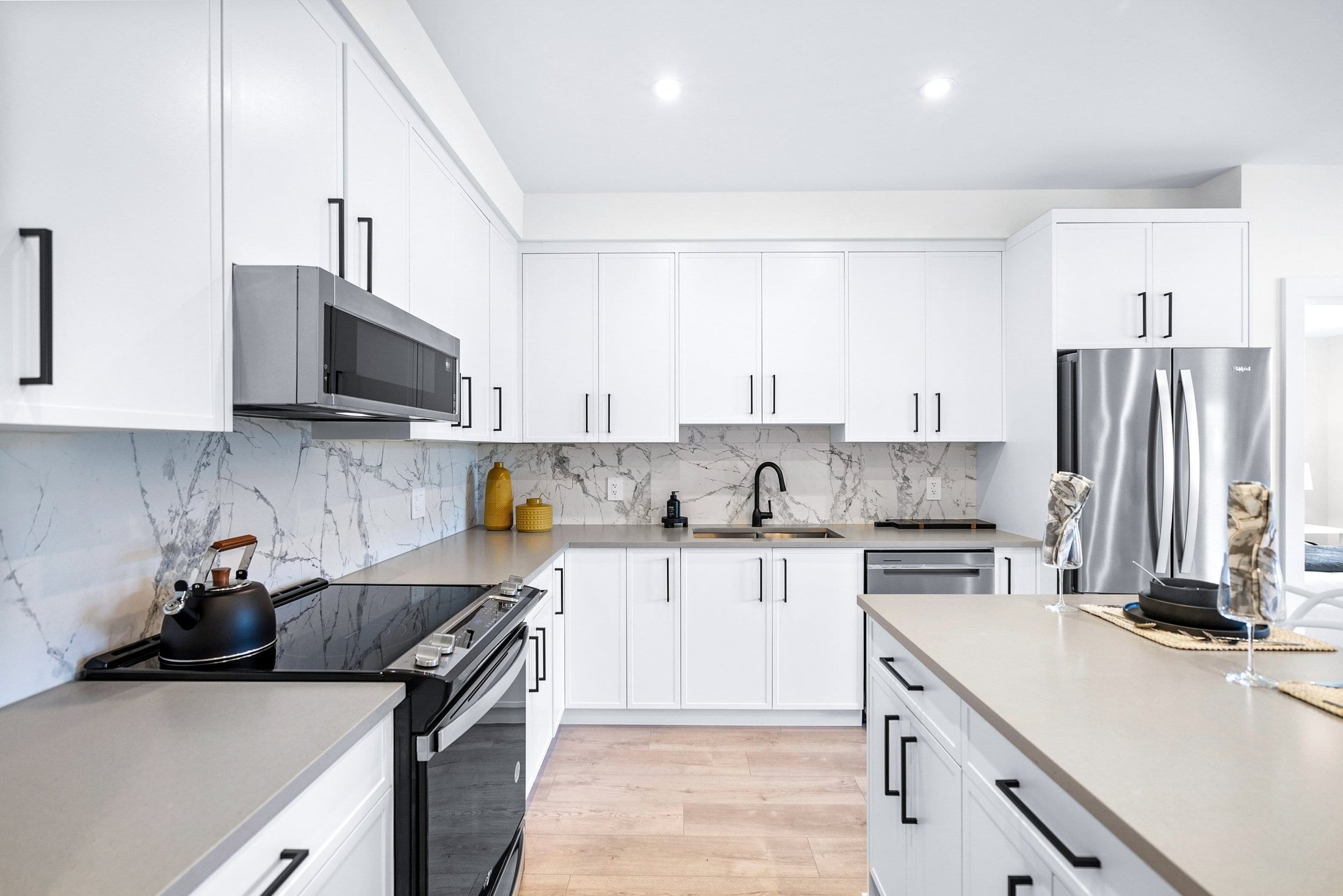White kitchen with marble backsplash and stainless steel appliances
